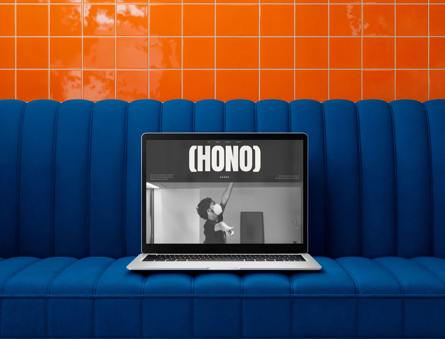 Portátil sobre un sofá azul mostrando la web HONO
