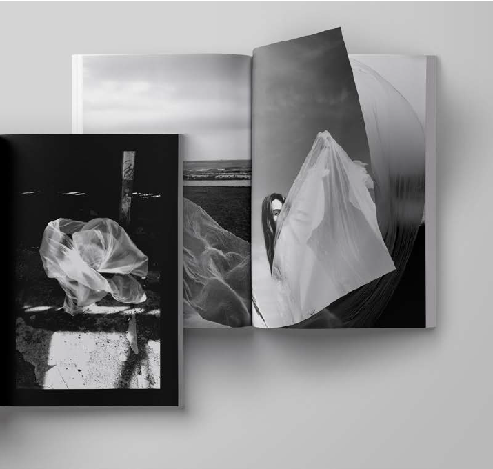 Fotolibro abierto con fotografías en blanco y negro de telas blancas en movimiento