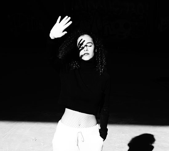 Mujer en blanco y negro con la mano sobre el rostro y su sombra proyectada
