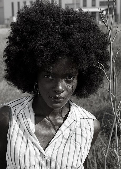 Retrato en blanco y negro de una mujer con el pelo rizado y camisa de rayas