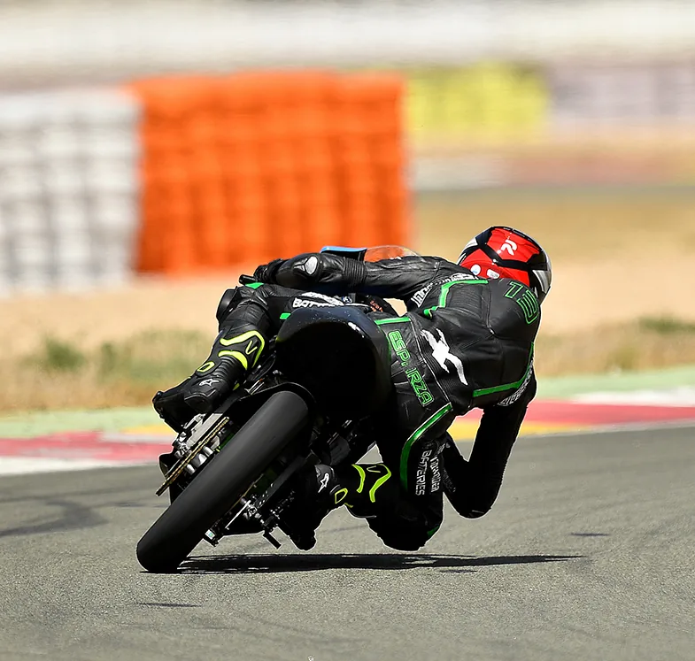 Piloto de una moto eléctrica inclinado en una curva de circuito