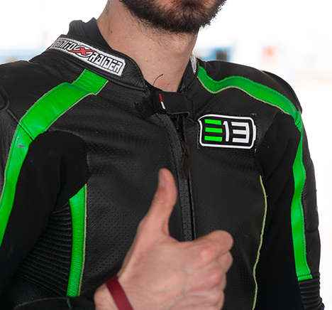 Mono de piloto negro y verde con el logotipo E13 en el pecho