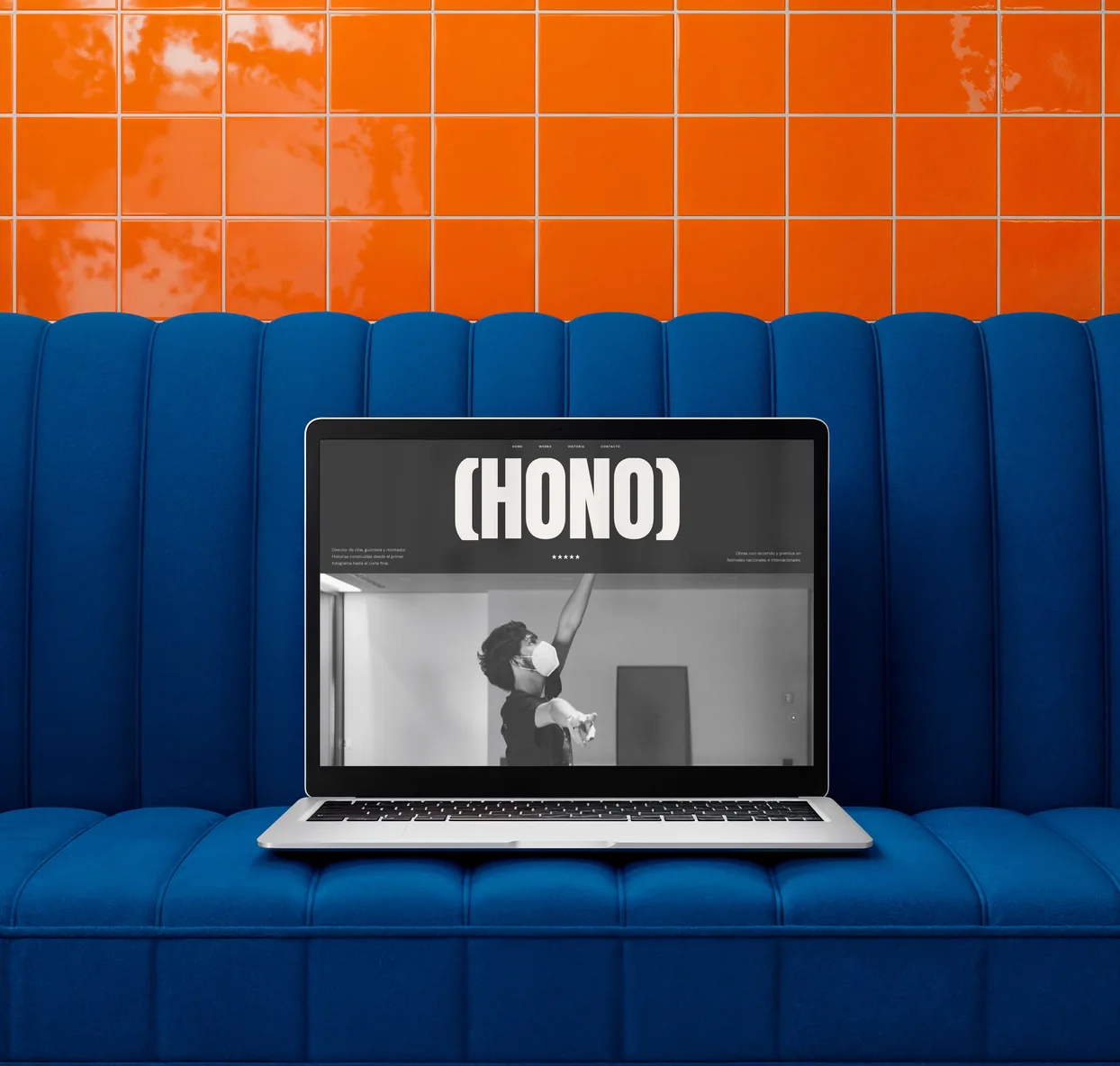 Portátil sobre un sofá azul mostrando la página de inicio de la web HONO