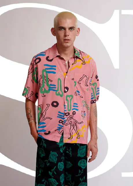 Modelo con camisa estampada rosa y verde sobre una letra tipográfica gigante