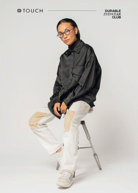 Modelo sentada en un taburete en un cartel de Touch Durable Eyewear Club