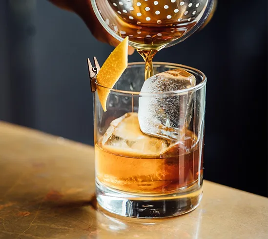 Vaso de whisky con hielo y piel de naranja